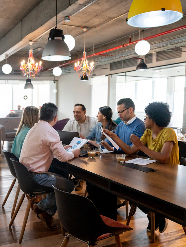Multi ethnic group of professionals at a coworking office in a meeting discussing something looking focused